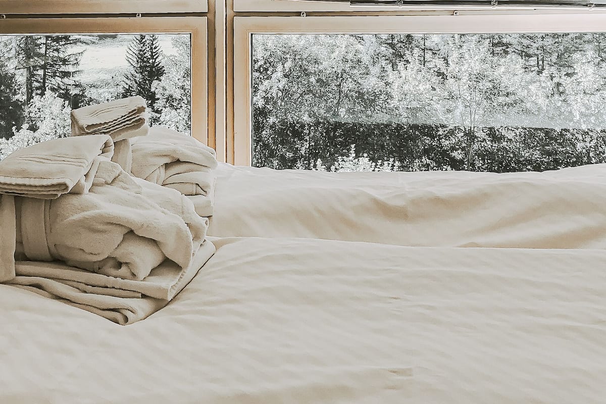 Un dormitorio con un ventanal grande, suelo de madera y una silla.
