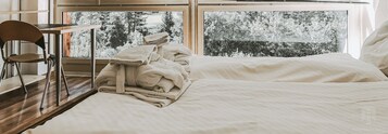 A bedroom with a large window, wooden floor, and a chair.