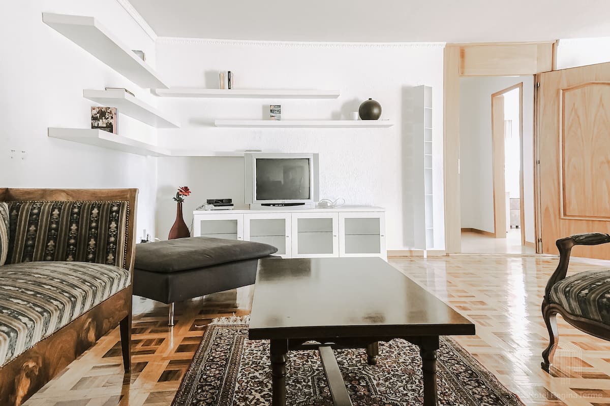 Una sala de estar con un sofá, una mesa de centro, un televisor y una estantería.