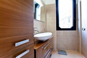 Une salle de bain moderne avec un meuble-lavabo en bois, un lavabo blanc et un grand miroir.