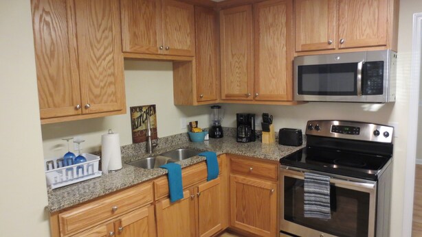 A kitchen with wooden cabinets, a granite countertop, a stainless steel microwave, a toaster, and a double oven. - Apartment In Downtown Durham (Durham)