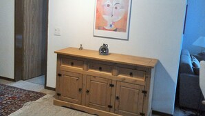 Une pièce avec un meuble en bois, une œuvre d’art encadrée accrochée au mur et une porte.