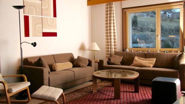 Un salon avec deux canapés, une table basse, une lampe et un fauteuil.