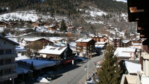 Une ville de montagne enneigée, avec des bâtiments en bois, une rue principale et une vue dégagée sur les collines environnantes.