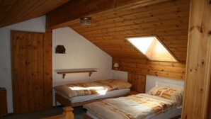 Une petite pièce chaleureuse, avec deux lits en bois, un plafond en pente et une lucarne.