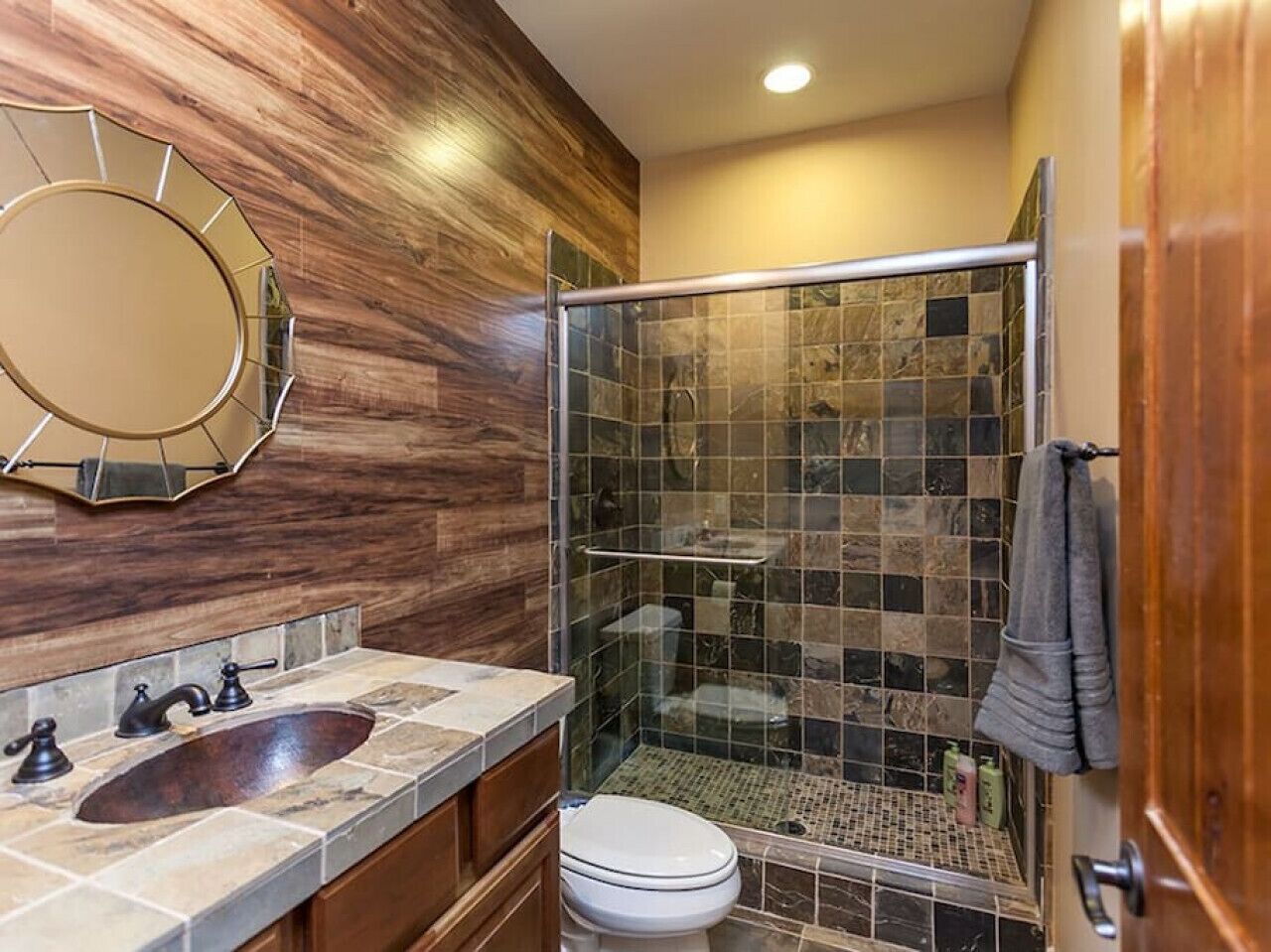 A bathroom with a wooden vanity, a sink, a toilet, and a glass-enclosed shower.