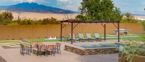 Zona de piscina con sillas de descanso, una mesa y una pérgola.