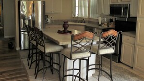 A modern kitchen with white cabinetry, stainless steel appliances, and a central island with bar stools. - Unbeatable Waterfront Deal: Special Offers on 4BR Luxury Canal Retreat (Welaka)