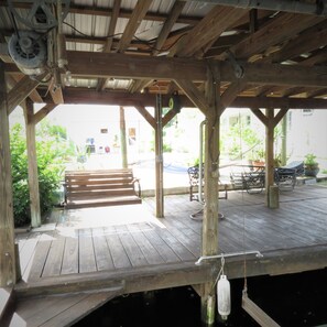 A wooden deck with a bench and tables, surrounded by greenery. - Unbeatable Waterfront Deal: Special Offers on 4BR Luxury Canal Retreat (Welaka)