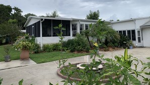 A two-story house with a covered porch and a garden area in front. - Unbeatable Waterfront Deal: Special Offers on 4BR Luxury Canal Retreat (Welaka)