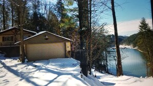 A cabin with a garage, surrounded by snow-covered ground and trees, overlooking a lake. - Lake Watauga FAMILY FUN, Sunny Lake Front Home  Private Dock  Water Toys WiFi (Butler)