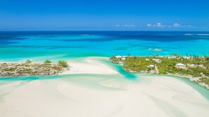 Eine Luftaufnahme einer tropischen Insel mit klarem türkisblauem Wasser, weißen Sandstränden und vereinzelter Vegetation.