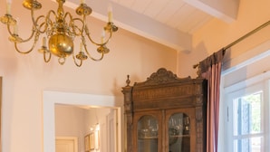 A wooden dining table with a patterned rug, a chandelier, and a wooden cabinet with glass doors. - Acropolis Villa (Athens)