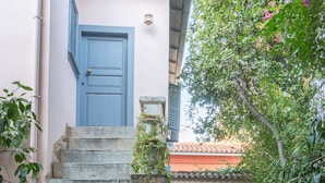 A stone staircase leading to a blue door, surrounded by potted plants and a stone pathway. - Acropolis Villa (Athens)