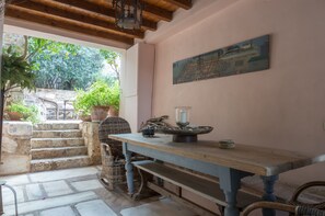 Enjoy a warm and inviting space with a long table, a framed painting, and a stone staircase leading to an outdoor area with a view.