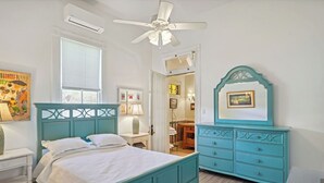 A bedroom with a bed, a dresser, a ceiling fan, and a window.