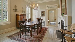 A dining room with a wooden table and chairs, a chandelier, and a fireplace.