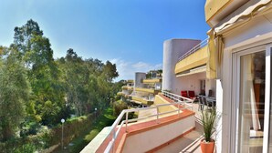 Un hôtel doté d’un balcon donnant sur un jardin luxuriant et des arbres.