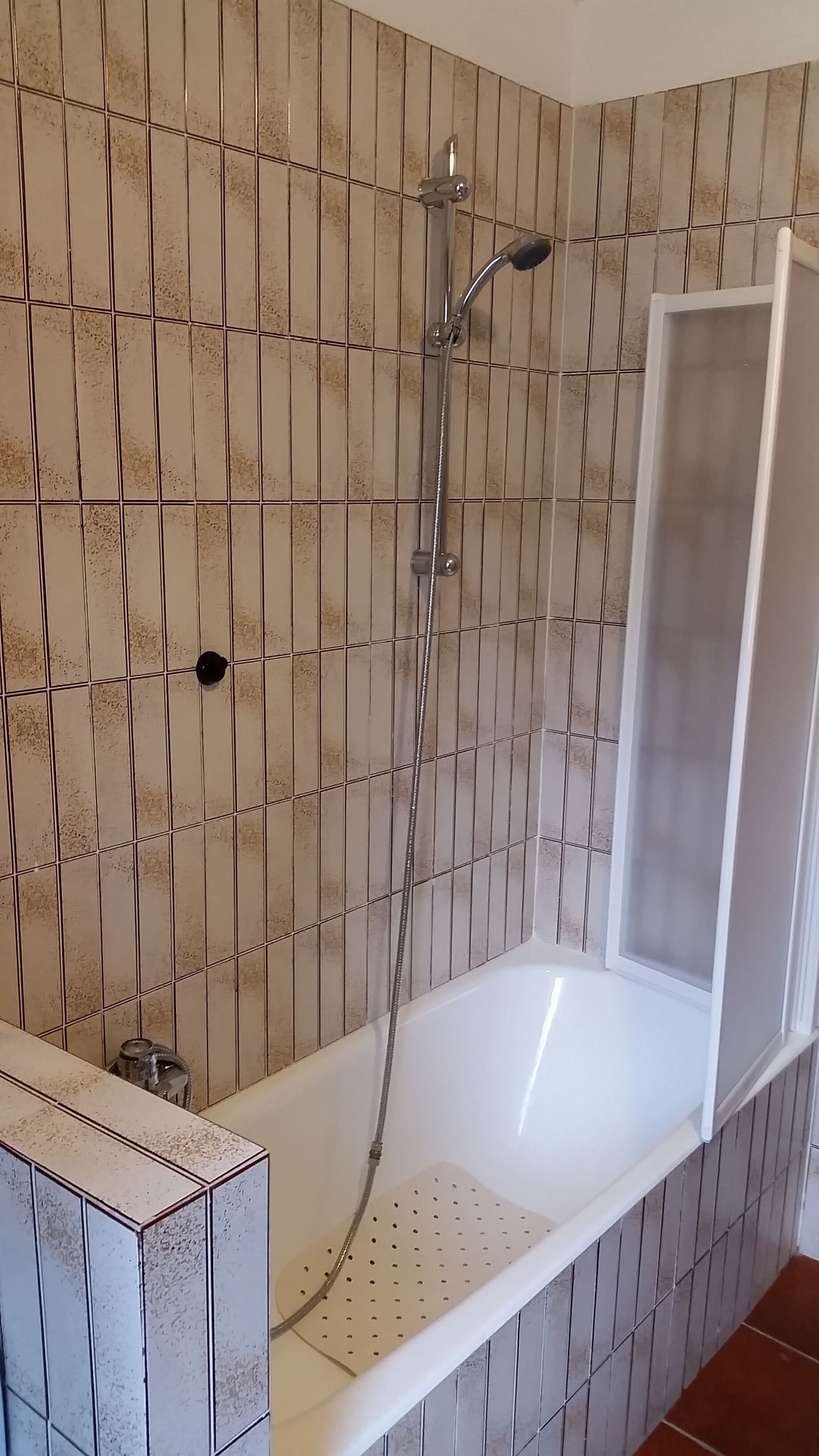 Une cabine de douche dotée d’un siège intégré et d’un pommeau de douche à main.