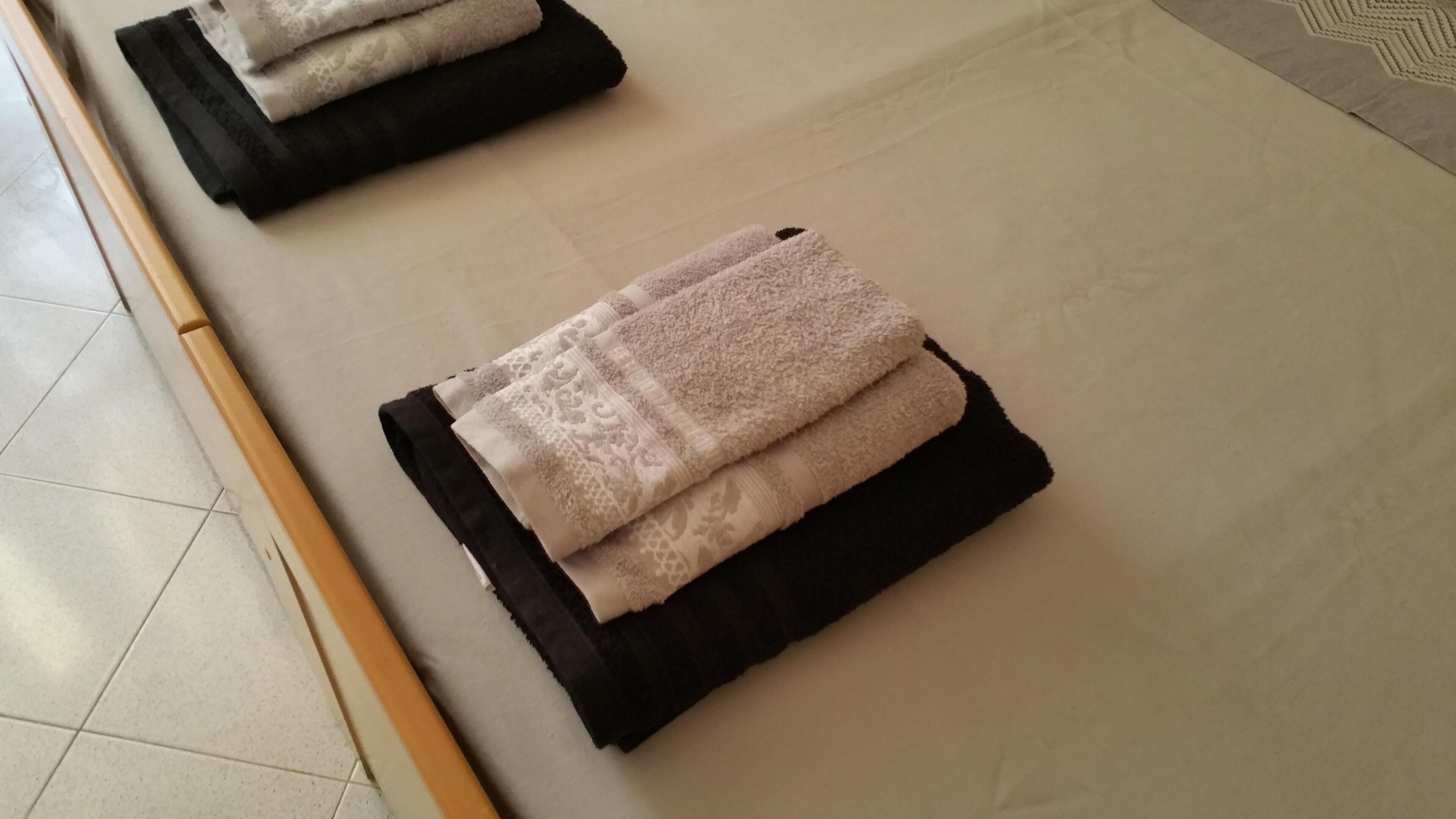 A neatly folded towel on a black mat in a room with a tiled floor.