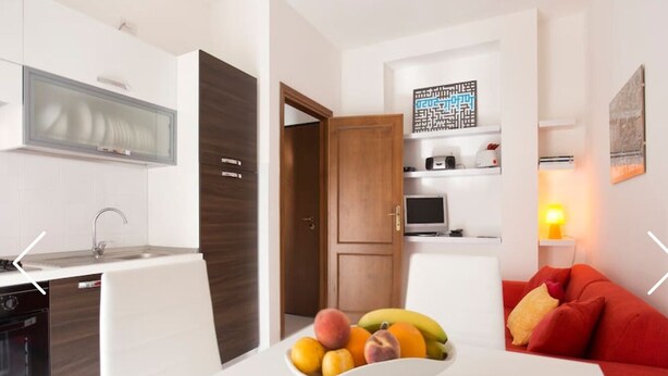 Eine moderne Küche mit weißen Schränken, einer eingebauten Mikrowelle und einem Essbereich mit weißem Tisch und rotem Sofa.