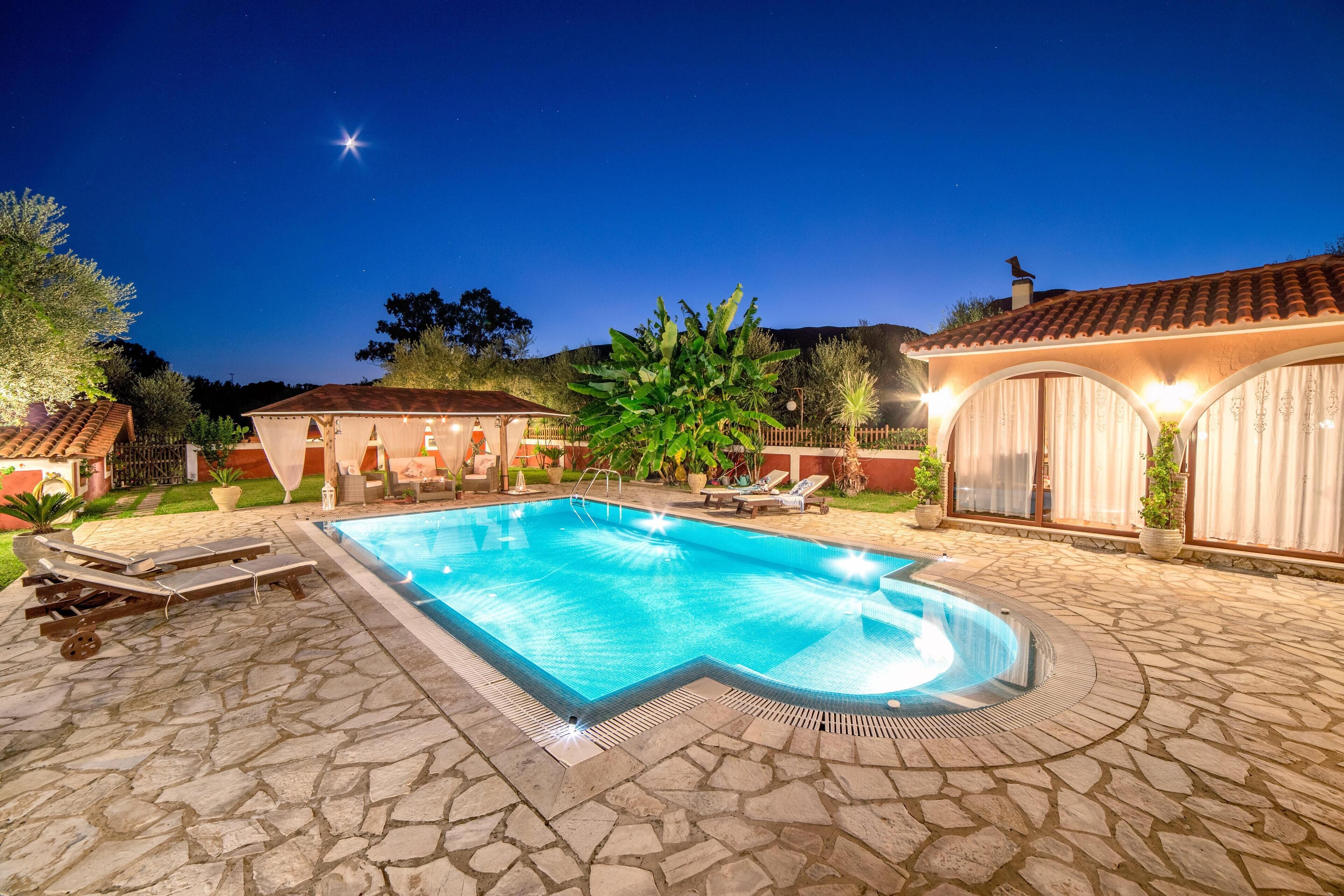Una piscina con baldosas de piedra, sillas de descanso y una zona de patio cubierta.