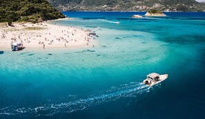 A beach with clear turquoise waters, a boat, and a lifeguard tower.