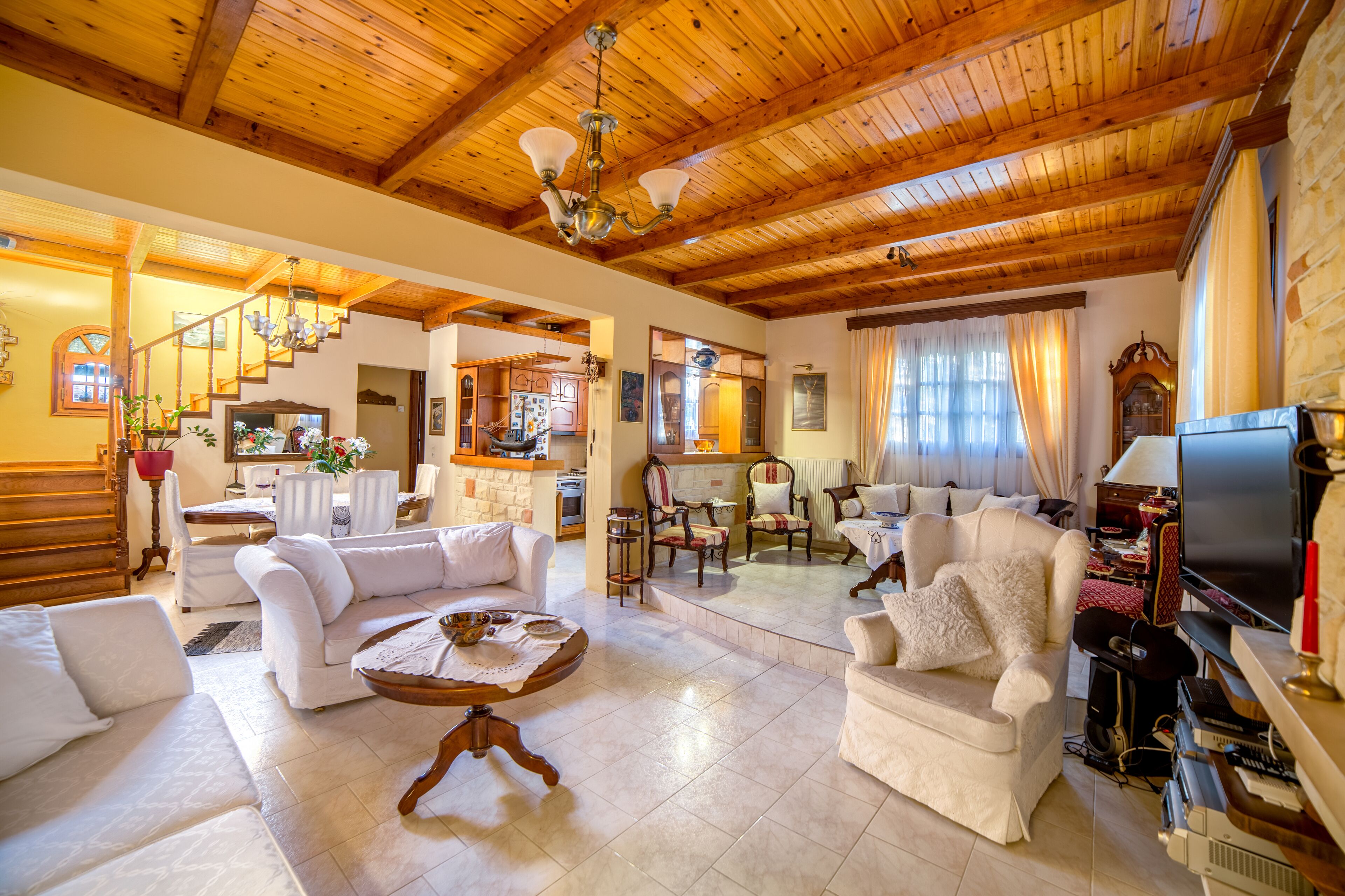 A spacious living room with a high wooden ceiling, a television, and a fireplace.