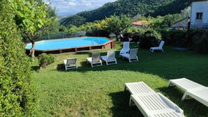 A backyard with a swimming pool, surrounded by white lounge chairs and a grassy lawn. - Villa La Panoramica (late 18th-century mansion) suitable for large groups. (Cingoli)