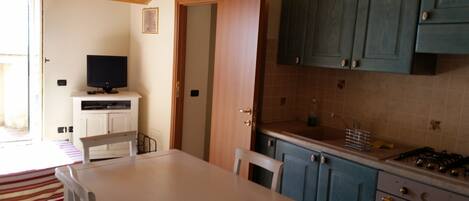 A kitchen with a dining table, chairs, a TV, and cabinets.