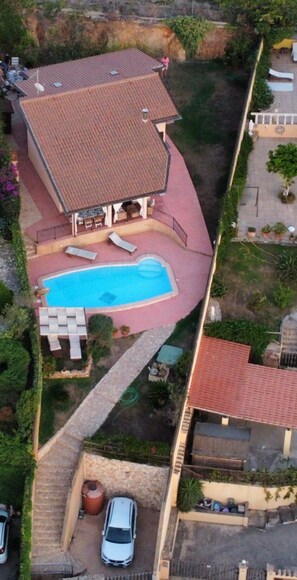 Eine Luftaufnahme eines Grundstücks mit Swimmingpool, überdachter Terrasse und einem Auto auf der Auffahrt.