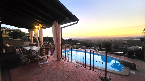 Une terrasse sur le toit avec une piscine, du mobilier d’extérieur et une vue sur le paysage urbain au coucher du soleil.