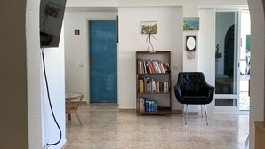 A spacious living area with a blue door, a bookshelf, a black chair, and a wooden chair. - AroeiraMIR - Villa with private pool and garden, Lisbon South Bay [38274 / AL] (AROEIRA)