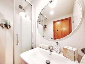 Un baño con un lavabo blanco, un espejo, una puerta de madera y un perchero para toallas.