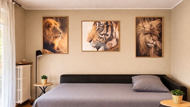 Ein Schlafzimmer mit einem Bett, einem Heizkörper, einem kleinen Tisch mit einer Pflanze und drei gerahmten Tierbildern an der Wand.