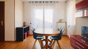 Ein Essbereich mit einem runden Tisch, vier Stühlen, einem roten Schrank und einem Fernseher auf der rechten Seite.