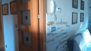 Ein Zimmer mit Holztür, einer Steinsäule mit integriertem Telefon und gerahmten Bildern an der Wand.
