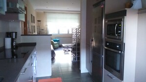 Eine moderne Küche mit Edelstahlgeräten, einer zentralen Kochinsel und Blick zum Wohnbereich.