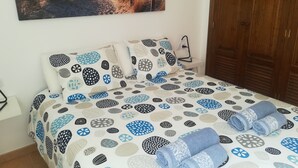 A bedroom with a bed, pillows, and a wall-mounted picture. - Odamar Órzola apartament (Órzola, Lanzarote)