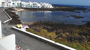 A coastal town with white buildings, a rocky shoreline, and a clear blue sky. - Odamar Órzola apartament (Órzola, Lanzarote)