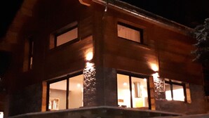 Une cabane en bois dotée de grandes fenêtres et reposant sur des fondations en pierre.