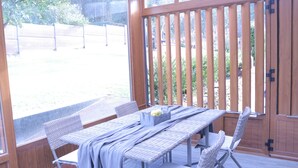 A covered patio area with a table and chairs, a wooden fence, and a view of a garden. - House in a natural setting, 200m from the beach in Costa da Morte (Balarés)