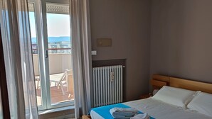 A hotel room with a bed, a radiator, a window with curtains, and a view of the outside. - penthouse apartment in the center of Monopoli   (Monopoli)