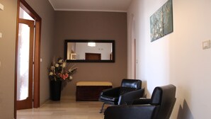A hallway with a wooden door, a potted plant, a bench, and two black chairs. - penthouse apartment in the center of Monopoli   (Monopoli)