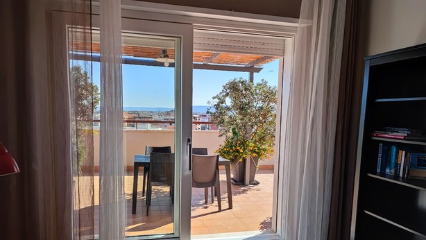A room with a sliding glass door leading to an outdoor patio with a table, chairs, and a potted plant. - penthouse apartment in the center of Monopoli   (Monopoli)