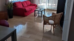 A modern living room with a red sofa, a wicker chair, a small table, and a potted plant. - penthouse apartment in the center of Monopoli   (Monopoli)