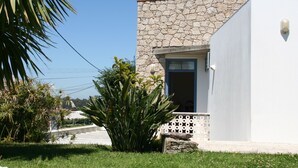 A building with a stone facade, a white exterior, and a red-tiled roof.