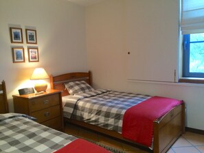 A bedroom with a bed, bedside table, lamp, and a window.
