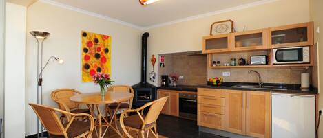 Una cocina compacta con armarios de madera, microondas, tostadora y un lavamanos.