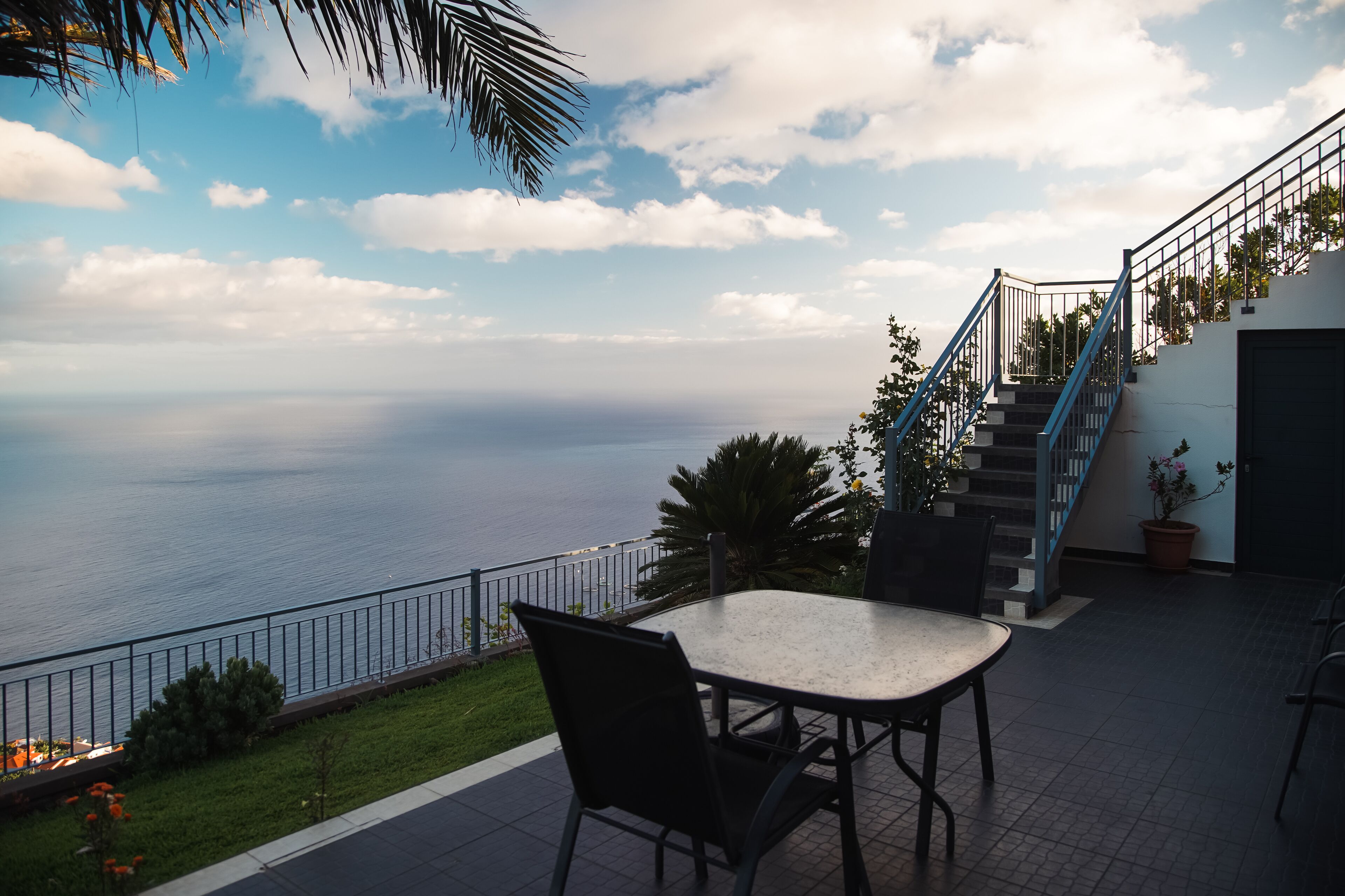 A terrace with a table and chairs overlooking a coastal view.
